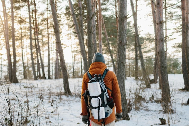 Voyageur homme avec sac à dos randonnées en hiver paysage forestier enneigé voyage aventure concept de vie vacances actives en plein air par temps froid dans la nature