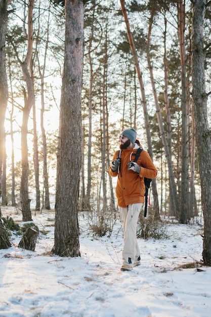 Voyageur homme avec sac à dos randonnées en hiver paysage forestier enneigé voyage aventure concept de vie vacances actives en plein air par temps froid dans la nature