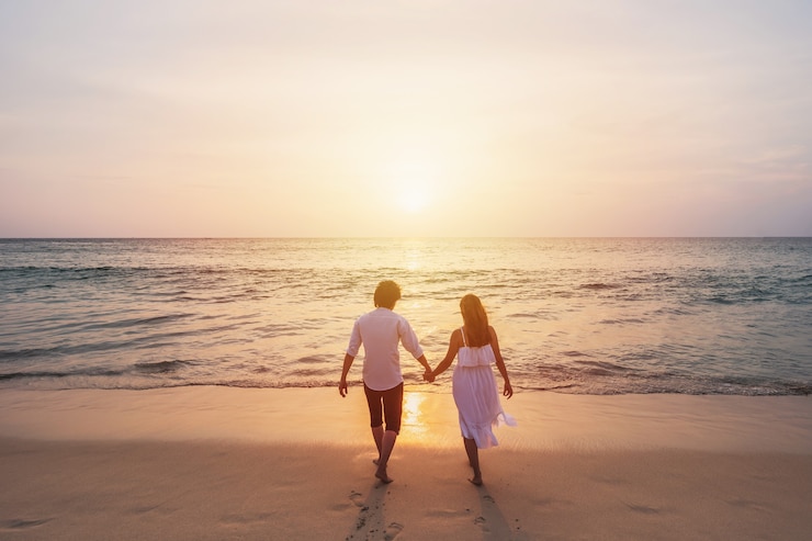 Photo voyageur jeune couple à la recherche de beau coucher de soleil sur la plage