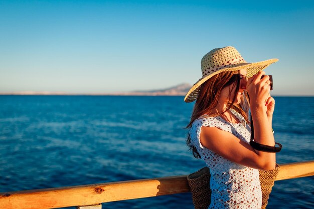 Voyageur de jeune femme prenant des photos de paysage de mer sur la jetée à l'aide de l'appareil photo Mode d'été Vacances d'été