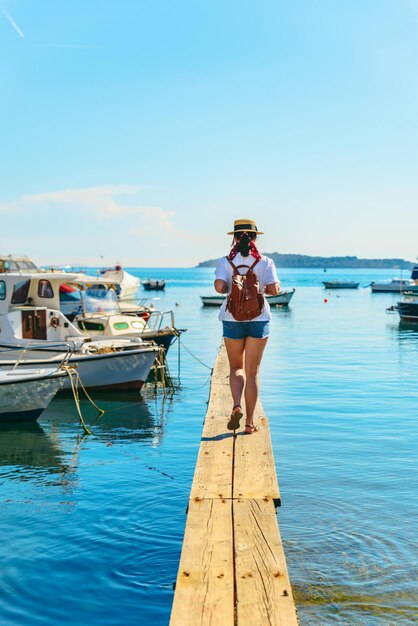 Voyageur de jeune jolie femme au quai en bois dans la baie de la mer