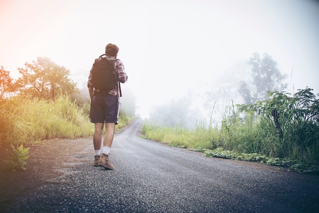 Voyageur marchant le long de la route vers les montagnes.