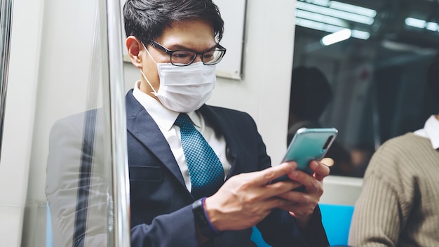 Voyageur portant un masque facial lors de l'utilisation d'un téléphone portable dans un train public