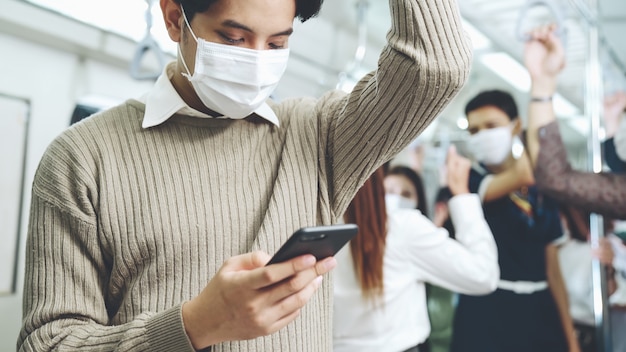 Voyageur portant un masque tout en utilisant un téléphone mobile dans un train public