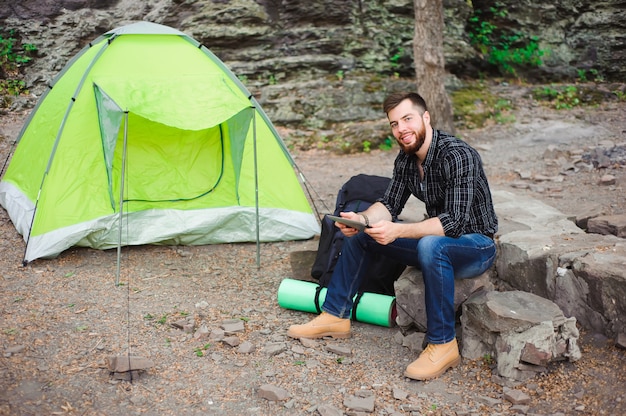 Voyageur Près D'une Tente Avec Une Tablette Le Soir.