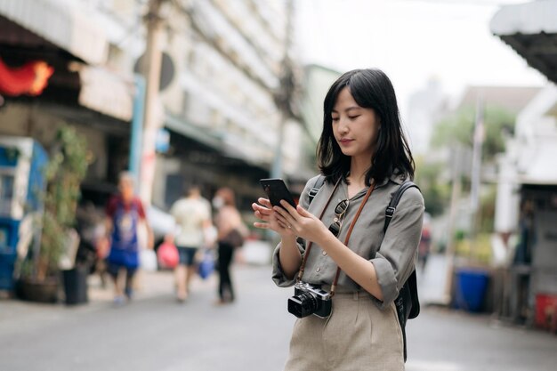 Voyageur de sac à dos jeune femme asiatique à l'aide de téléphone mobile appréciant la place culturelle de la rue Voyageur vérifiant les rues secondaires