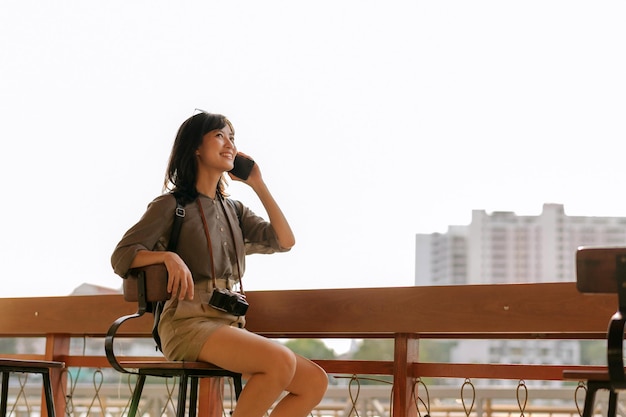 Voyageur de sac à dos de jeune femme asiatique utilisant un téléphone portable dans l'embarcadère express sur la rivière Chao Phraya à Bangkok