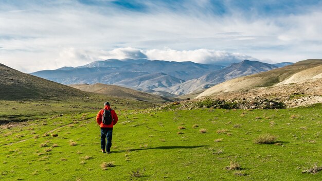 Un voyageur avec un sac à dos marche dans une vallée de montagne