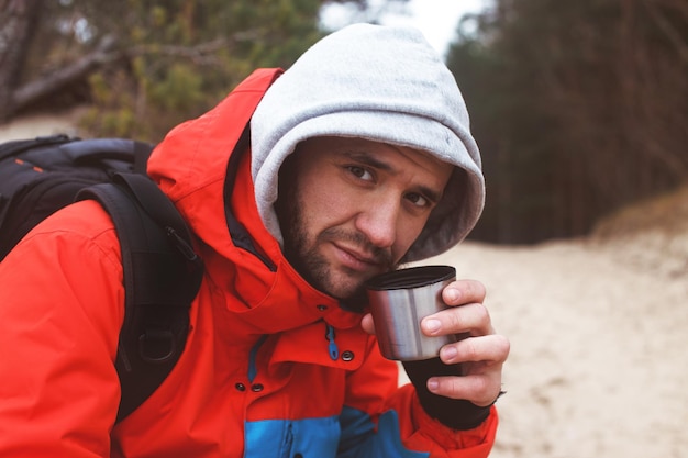 Voyageur tenant une tasse avec un tee chaud sur fond de forêt