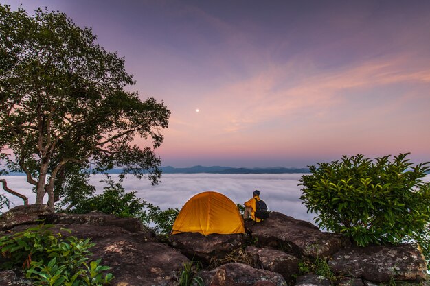 Le voyageur et la tente orange sur la haute montagne et la mer de brouillard.