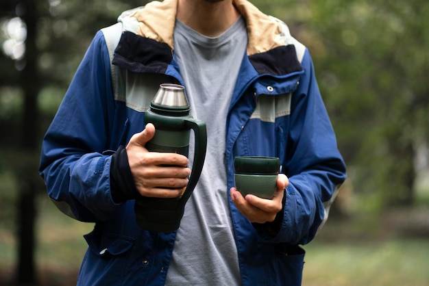 Un voyageur touristique verse de l'eau chaude à partir d'un thermos