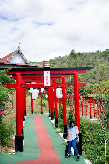 Des voyageurs asiatiques des femmes thaïlandaises voyagent en posant un portrait avec la porte torii rouge du temple Wat Khao Sung Chaem Fa sur la montagne Khao Sam Sip Hap dans le district de Tha Maka le 23 mai 2021 Kanchanaburi Thaïlande