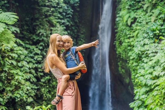 Voyageurs de maman et de fils sur le fond de la cascade de Leke Leke dans l'île de Bali en Indonésie. Voyager avec le concept d'enfants.