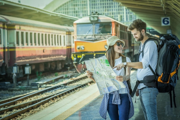 Les voyageurs multiethniques regardent la carte à la gare