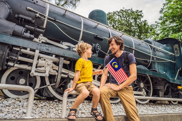 Voyageurs père et fils en malaisie avec le drapeau de la malaisie célébrant le jour de l'indépendance de la malaisie et le jour de la malaisie Concept de voyage en malaisie