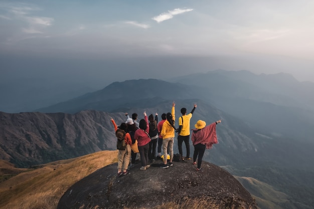 Les voyageurs de randonnée groupent des chemises colorées debout au milieu d'une vue sur la montagne du pré doré. Pointez votre doigt vers leur propre destination. À Mulayit Taung au Myanmar.