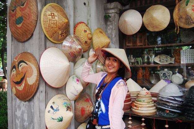 Photo les voyageurs thaïlandais voyagent visiter et faire du shopping sélectionner un chapeau de paille vietnamien dans une boutique de souvenirs locaux dans le quartier de la vieille ville de ba dinh à dong kinh nghia thuc square à hoan kiem à hanoi vietnam