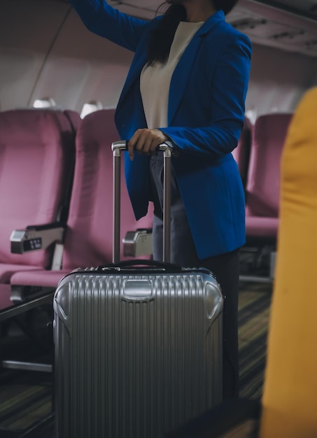 Photo voyageuse asiatique mettant des bagages dans un casier aérien lors de l'embarquement