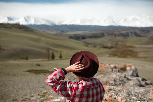 Voyageuse avec un chapeau sur le fond des montagnes