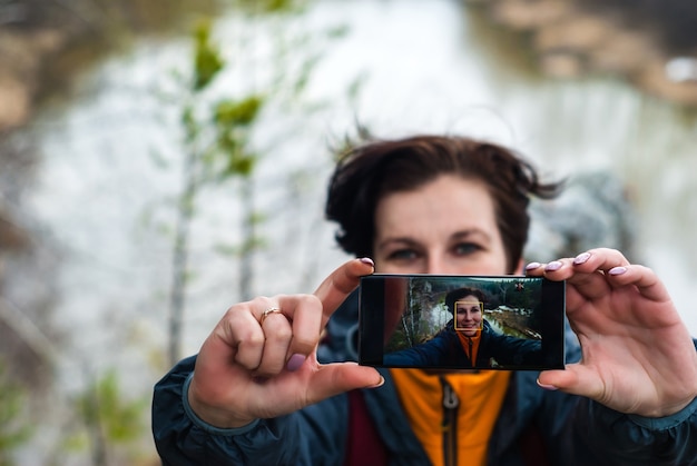 Une voyageuse fait un selfie au sommet d'une falaise au-dessus de la rivière Spring