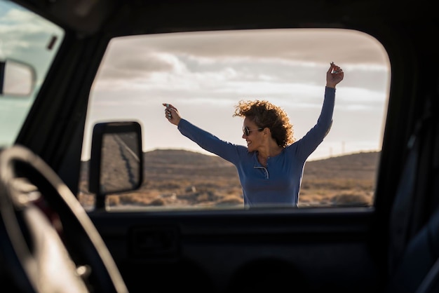 Une voyageuse heureuse et excitée saute folle en s'amusant à la destination d'arrivée vue de l'intérieur de la voiture