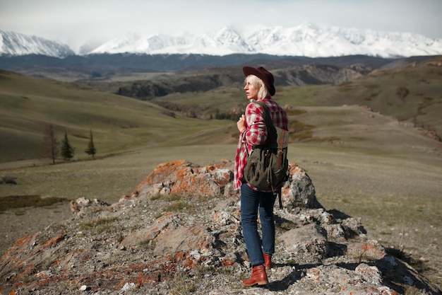 Une voyageuse hipster avec un chapeau et un sac à dos sur le fond des montagnes