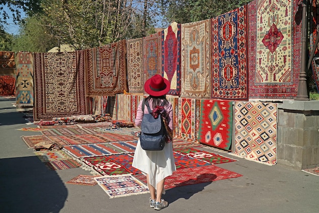 Voyageuse impressionnée par les superbes tapis du marché de vernissage au centre-ville d'Erevan, en Arménie