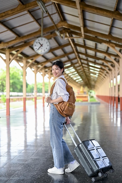 Une voyageuse avec sa valise prenant le train sur le quai de la gare