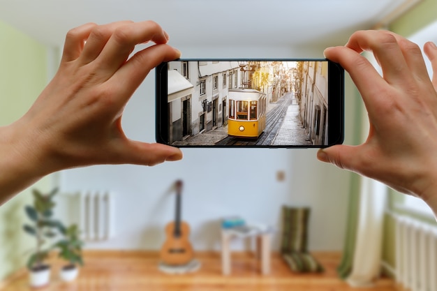 Photo voyagez à la maison. voyage en ligne à lisbonne, portugal via smartphone. tramway jaune légendaire à l'écran