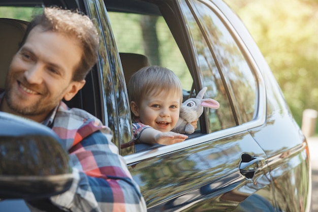 Photo voyagez en voiture en famille en famille, père et fils se penchent par la fenêtre