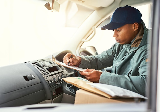 Voyons où aller ensuite Plan d'un coursier écrivant sur un presse-papiers alors qu'il était assis dans une camionnette de livraison