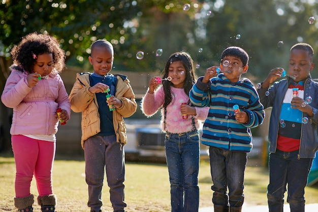 Voyons qui peut souffler la plus grosse bulle Photo recadrée d'un groupe de petits enfants faisant des bulles ensemble à l'extérieur