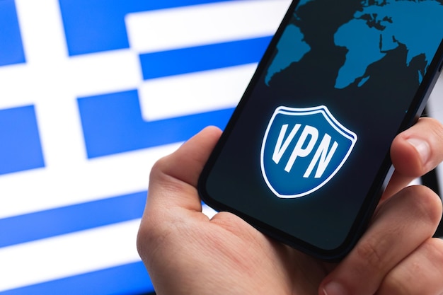 VPN en Grèce Concept Internet sécurisé et sécurisé Confidentialité Main avec téléphone portable et application VPN Drapeau et ordinateur portable sur la photo d'arrière-plan