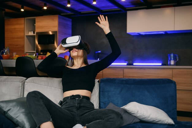 VR. Excité fille millénaire utilisant un casque de réalité virtuelle jouant à un jeu vidéo en intérieur. Focus sélectif