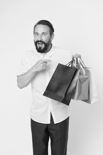 Vrai bonheur hipster caucasien brutal avec moustache shopping Homme barbu avec des sacs à provisions Joyeuses fêtes grande vente dans un centre commercial Hipster mature avec barbe Shopping bonheur