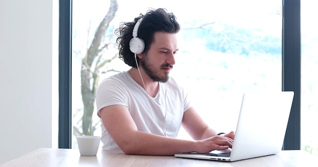 Vrai homme utilisant un ordinateur portable à la maison, boire du café en profitant de la détente