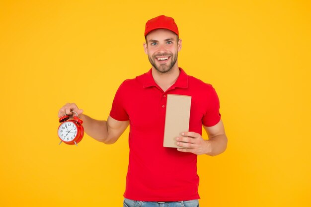 Photo vrai plaisir de faire des achats en ligne livraison pendant la quarantaine délai de livraison de l'homme du personnel amical courrier de livraison avec horloge tenant la boîte prenez votre colis livreur de cadeaux tenant l'horloge vintage