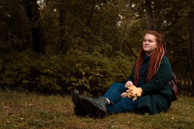 une vraie femme adulte assise sur l'herbe dans un parc ou une forêt