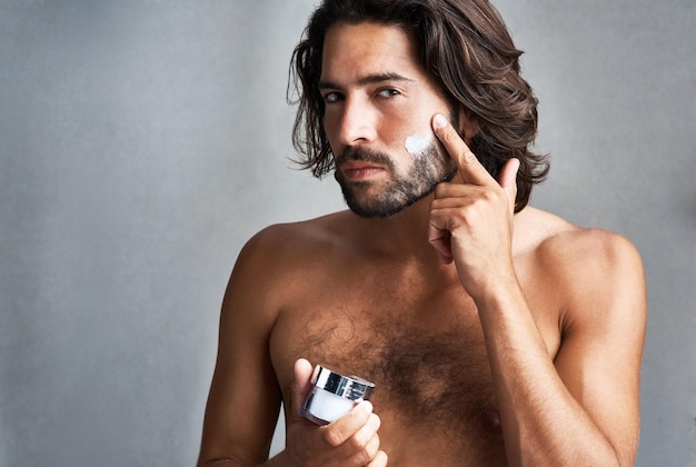 De Vrais Hommes Hydratent Prise De Vue En Studio D'un Beau Jeune Homme Appliquant Une Crème Hydratante Sur Son Visage Sur Un Fond Gris