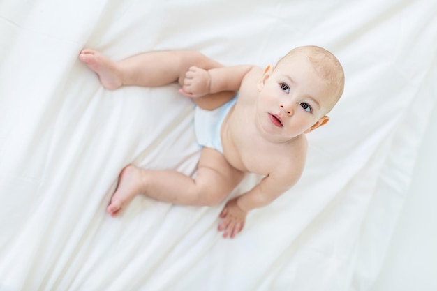 Vue aérienne de l'adorable petit garçon assis sur le lit concept de bébé de 1 an