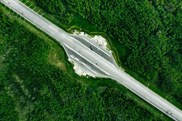 Vue aérienne de l'autoroute à péage avec parking dans la forêt de pins verts