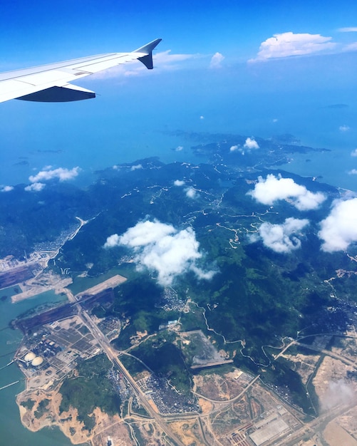 Photo vue aérienne d'un avion survolant un paysage contre un ciel bleu