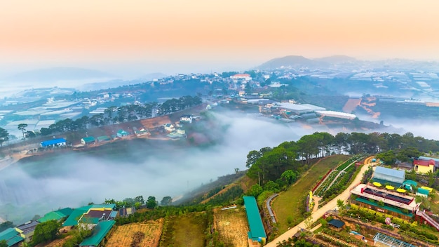 Vue aérienne des banlieues de Xuan Tho près de la ville de Da Lat le matin avec le ciel brumeux et le lever du soleil