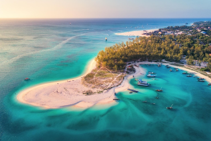 Photo vue aérienne des bateaux de pêche sur la côte de la mer tropicale avec plage de sable au coucher du soleil vacances d'été sur l'océan indien zanzibar afrique paysage avec bateau arbres verts eau bleue transparente vue de dessus