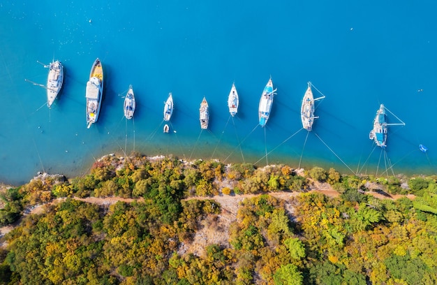 Vue aérienne de beaux yachts et bateaux sur la baie de la mer au coucher du soleil en été île de Lefkada Grèce Vue de dessus des yachts de luxe voiliers bord de mer eau bleue transparente et forêt verte Voyage