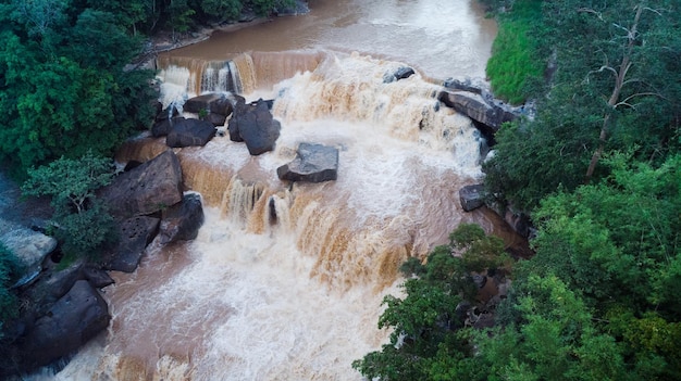 Vue aérienne de la belle cascade de la rivière naturelle et de la forêt verte avec des montagnes pour le fond