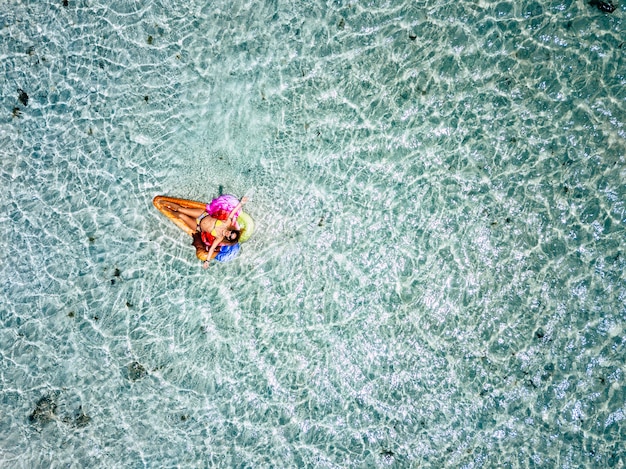 Vue Aérienne. De Belles Personnes De Race Blanche Touriste Femme Adulte Jeter L'aube Et Se Détendre Sur Un Lilo Coloré à La Mode Avec De L'eau De Mer Tropicale Transparente Et Propre Autour - Concept De Vacances D'été Et Hap