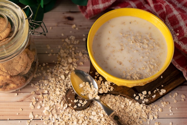 Une vue aérienne d'un bol de lait et de flocons d'avoine et un pot de biscuits aux raisins secs à l'avoine.