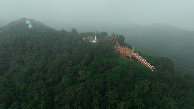 Vue aérienne à la brume matinale Wat Phra That Doi Phra Chan et Bouddha Daibutsu sur la montagne verdoyante