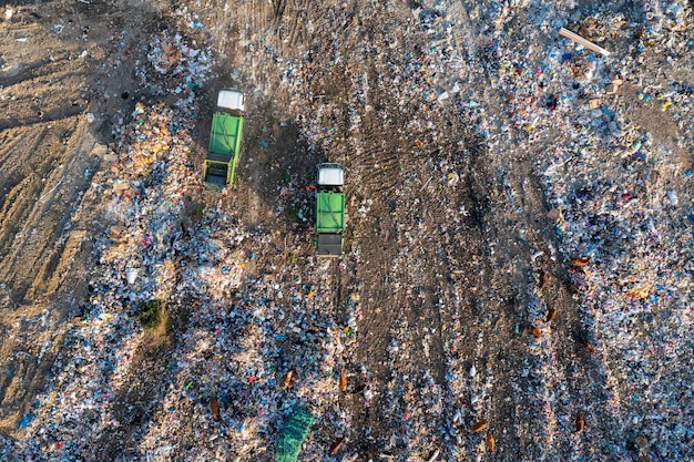 Vue aérienne d'un camion d'ordures déchargant un tas de déchets sur une décharge avec des vaches déversant des déchets non triés